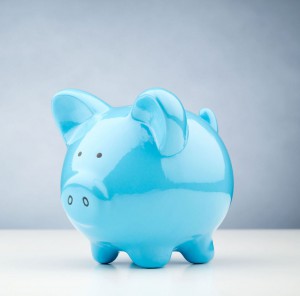 Blue Piggy Bank on a Table Horizontal image of a blue piggy bank standing on a white desk surface with copy space on the background.